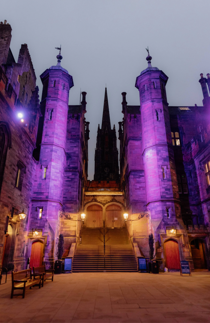 Colour photo of the New College Quad lit up purple
